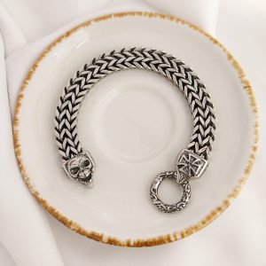 PULSERA DOBLE TRENZADO V CON BROCHE CRUZ Y CALABERA CON ARGOLLA GRABADA